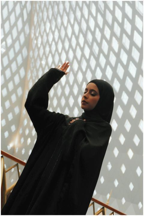 A woman in a black hijab poses elegantly with geom