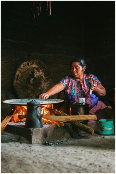 Indigenous woman cooking over an open flame in a r