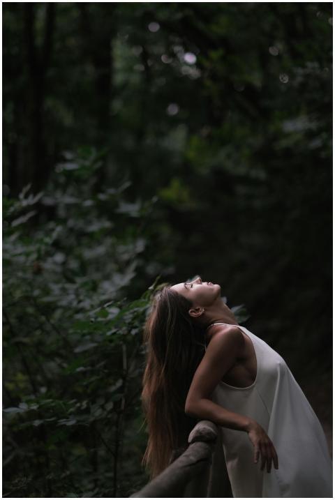 A woman peacefully leans back against a wooden rai