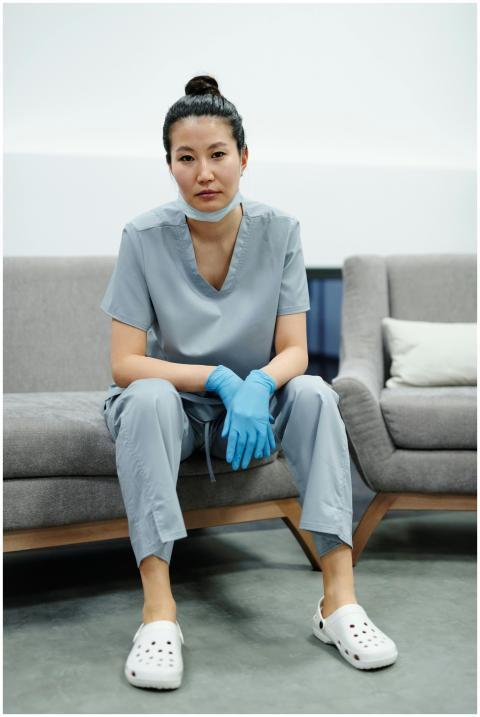An exhausted Asian doctor in scrubs and gloves sit