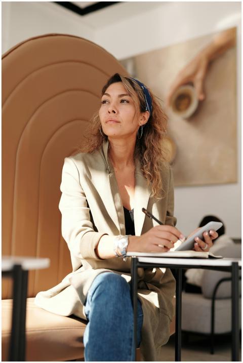 Confident woman in blazer taking notes with pen an