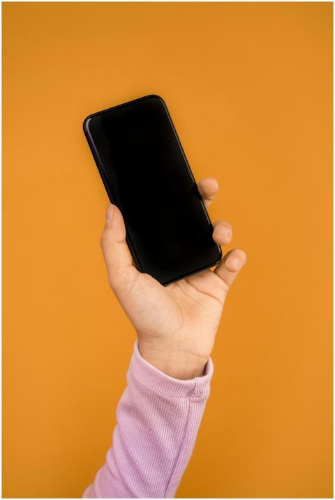 Close-up of a hand holding a smartphone against a