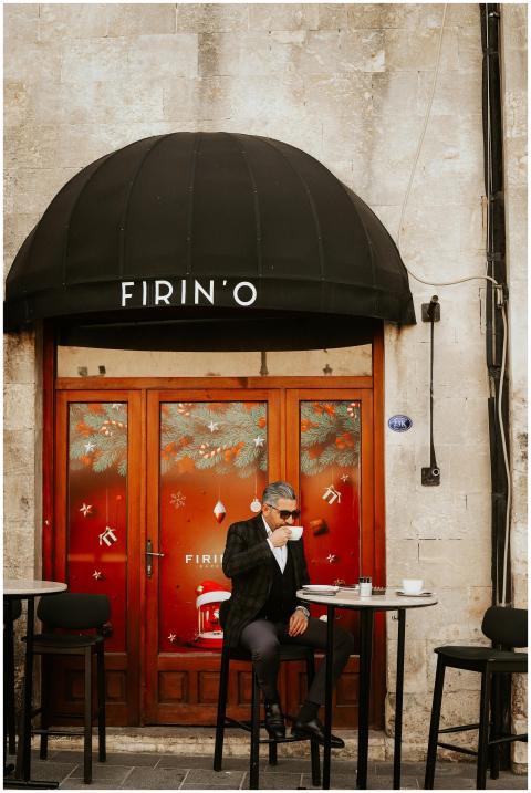 A man in a suit enjoys coffee at an outdoor café w