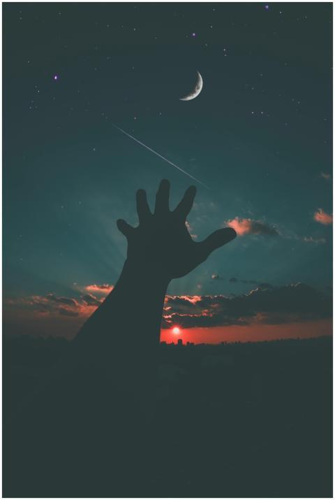 Silhouette of a hand reaching towards the crescent