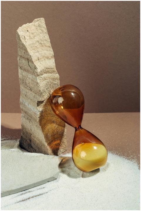 Amber hourglass resting against a stone with strea
