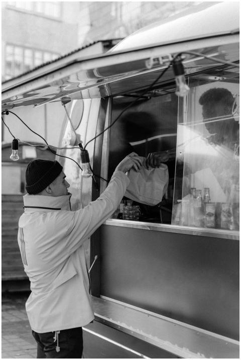 Black and white image capturing a man buying food