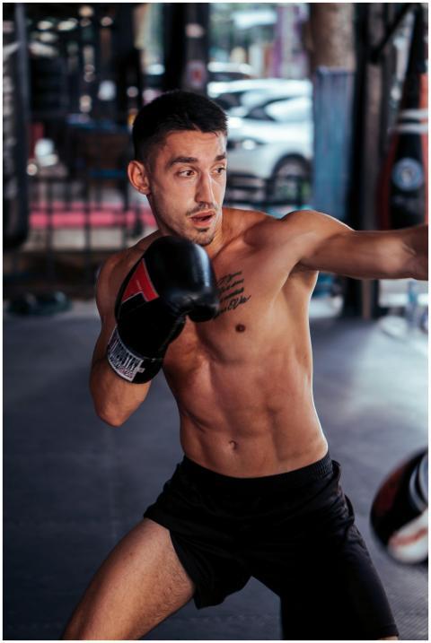 Shirtless male boxer trains intensely in a gym, sh