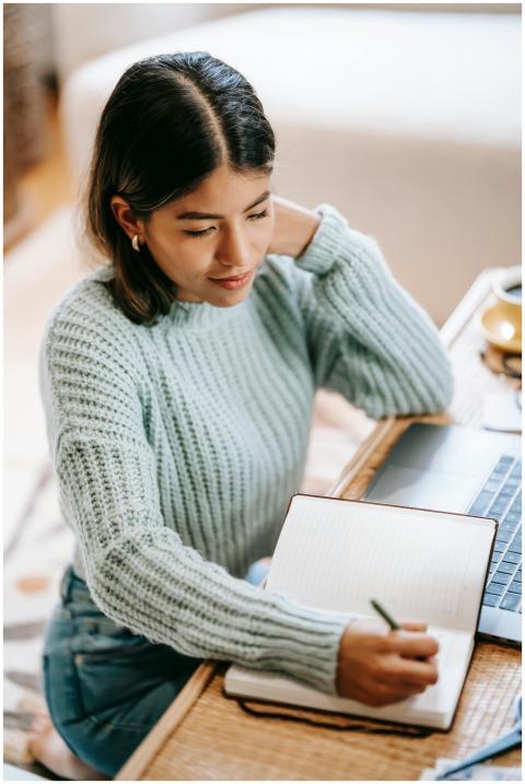 Hispanic woman studying with a laptop and notebook