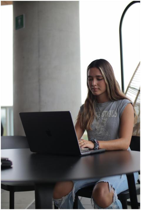 A young woman using a laptop at a desk, focused on