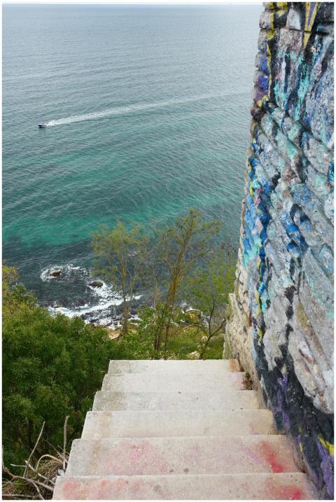 Graffiti-covered steps overlooking a serene ocean,