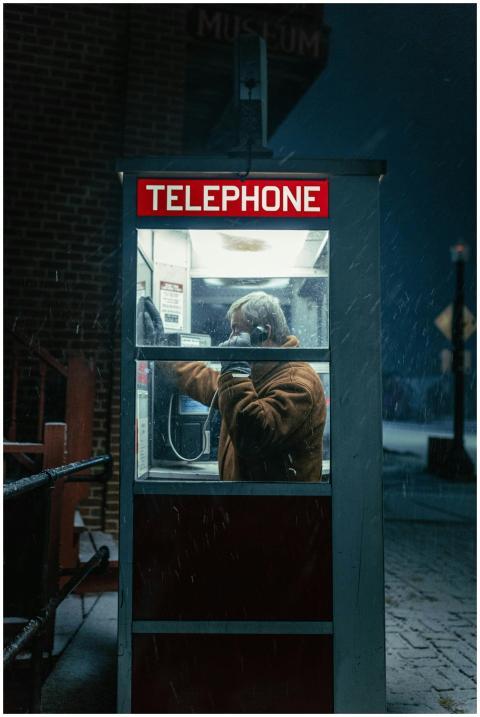 A man talking on the phone in a classic red teleph