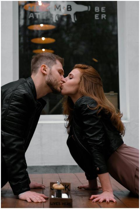 A couple shares a passionate kiss on a sidewalk ou