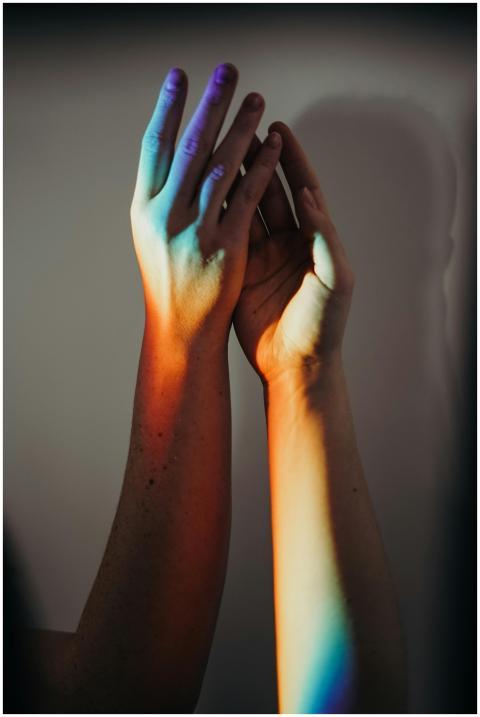 Two hands touched by rainbow colors, symbolizing u