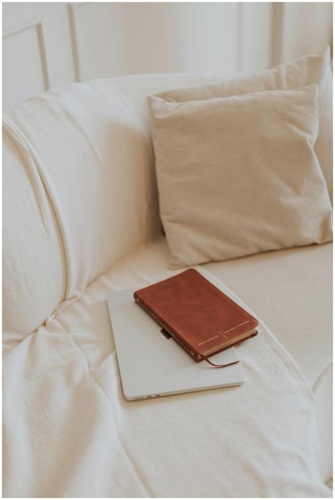 A leather notebook and tablet rest on a soft beige