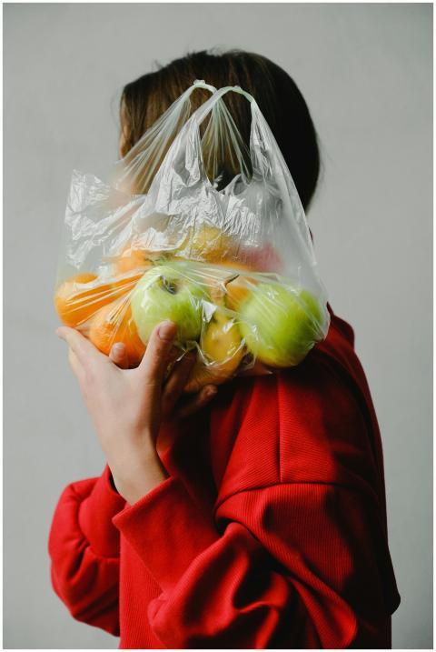 A person in a red sweater holds a plastic bag fill