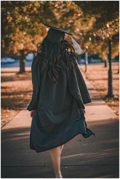 Back view of a graduate walking in an autumn park