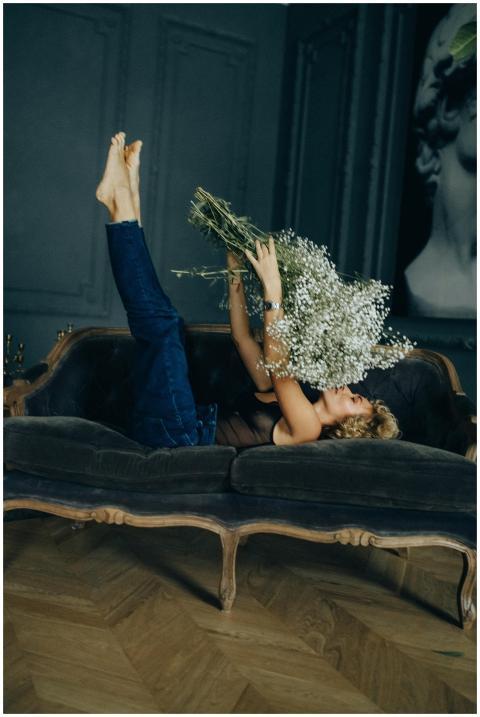 A woman lounging on a vintage sofa holding white f