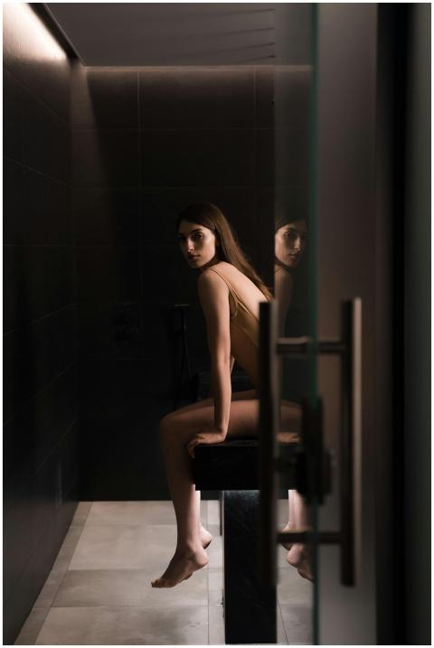 Woman in swimsuit seated in a dimly lit sauna room