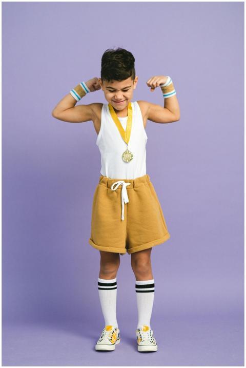 Joyful boy flexing with a medal, symbolizing victo