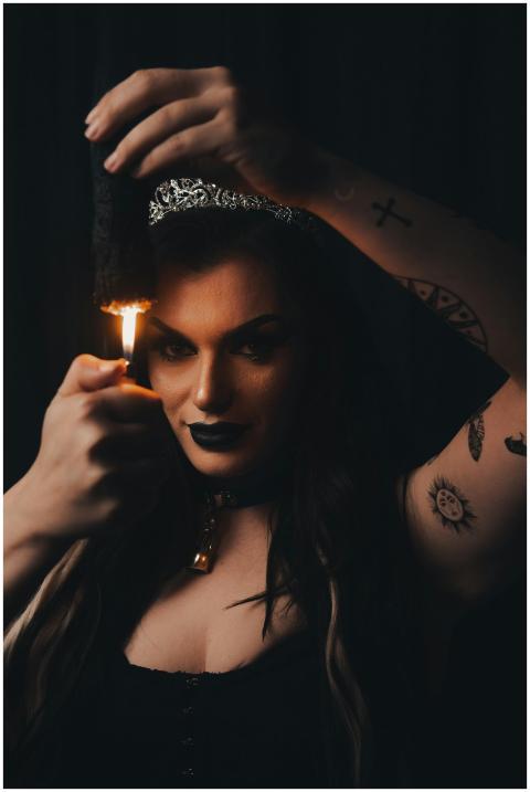 Dark portrait of a tattooed woman lighting a candl