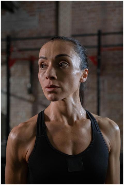 A fit woman looking away in a gym, showcasing musc