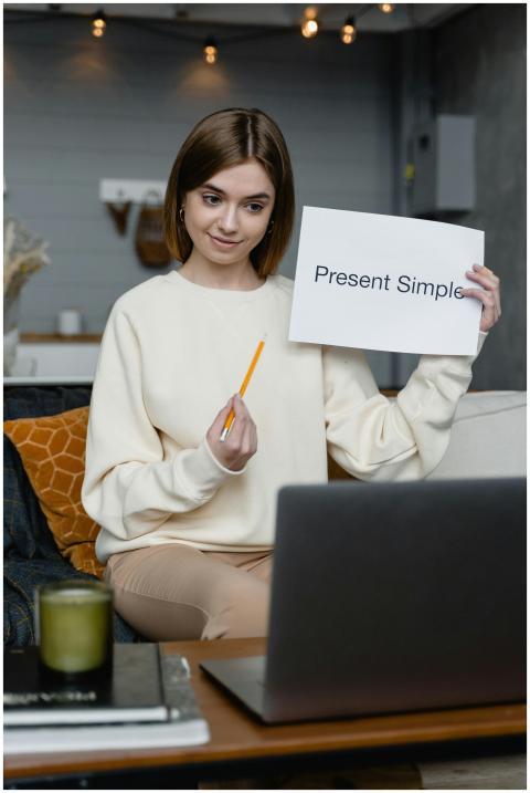 Woman teaching English online holding 'Present Sim