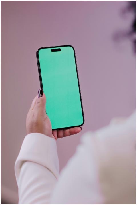 Close-up of a hand holding a smartphone with a gre