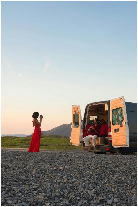 A couple enjoys a scenic sunset with their van, ca