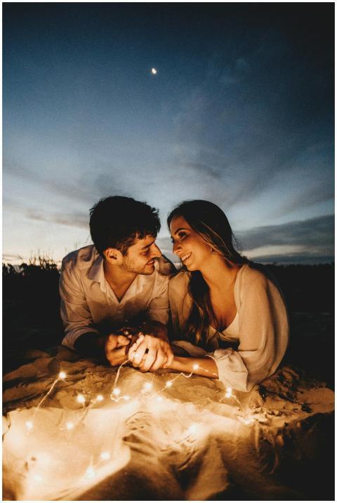 A loving couple lying on sandy ground, illuminated