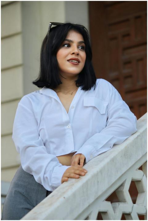 Young woman in white blouse posing confidently on