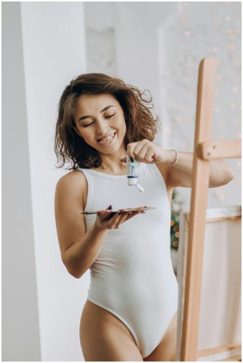 A woman in a swimming costume joyfully painting on