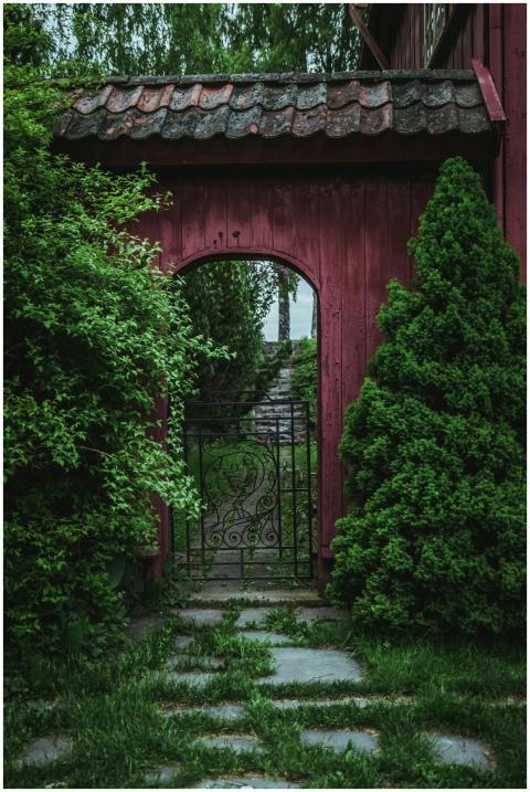 Rustic red garden gate surrounded by lush green fo