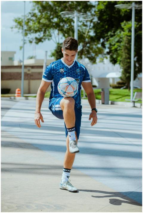 Young athletic man practices soccer tricks in sunn