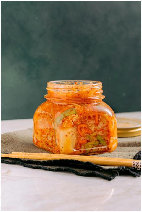 Close-up of homemade kimchi in a jar with chopstic