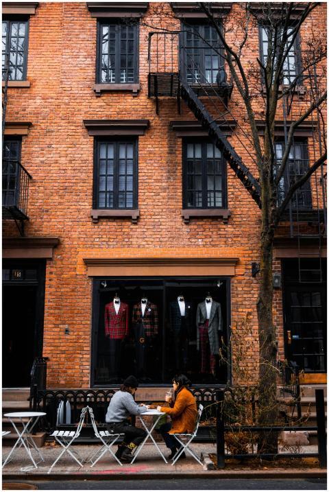 Two people sitting outside a brick building on a s