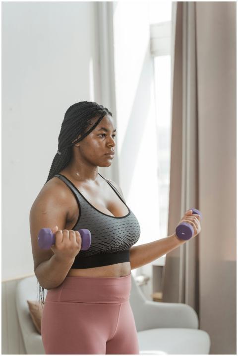 Curvy woman with braided hair working out with dum