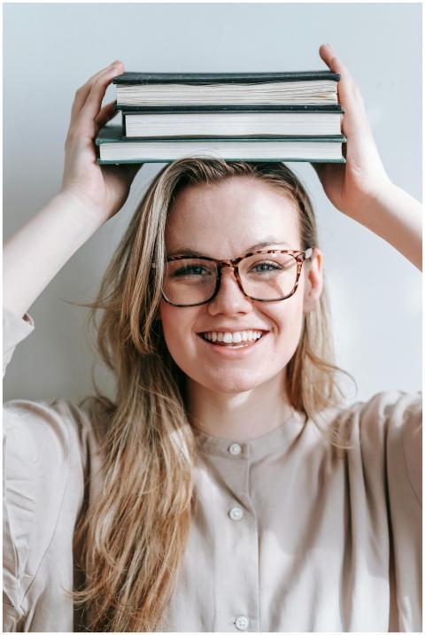 Young woman joyfully balancing books on her head,