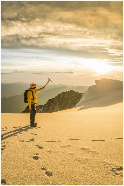 Mountain climber on a snowy peak at sunset, embrac