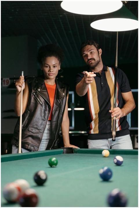 Two young adults engaging in a game of billiards,