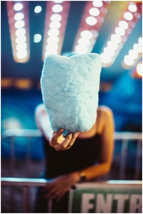 A person holds blue cotton candy with vibrant ligh