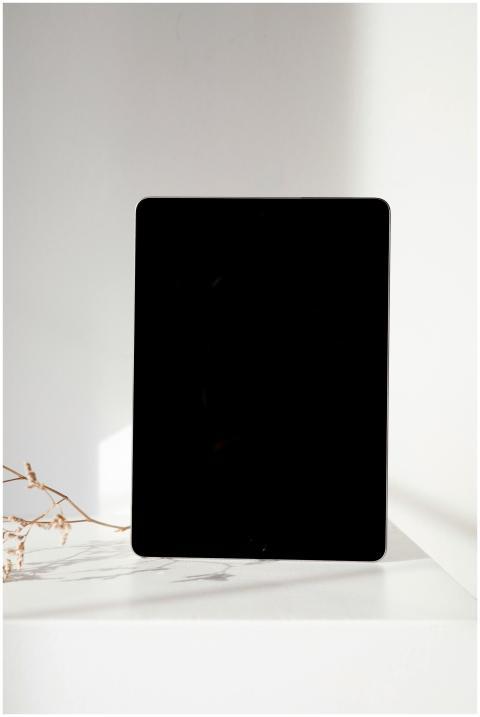 A sleek black tablet on a white surface with natur