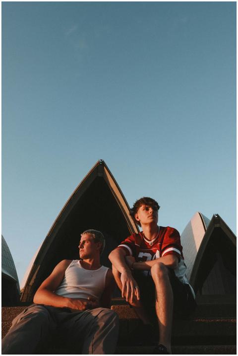 Two young adults sitting near Sydney Opera House,