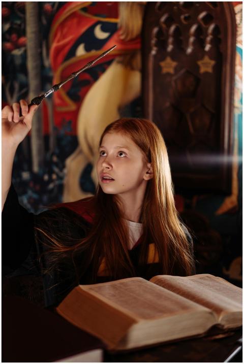 Young girl in costume practicing magic with a wand