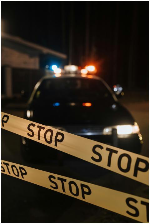 A police car with flashing lights behind a stop ta