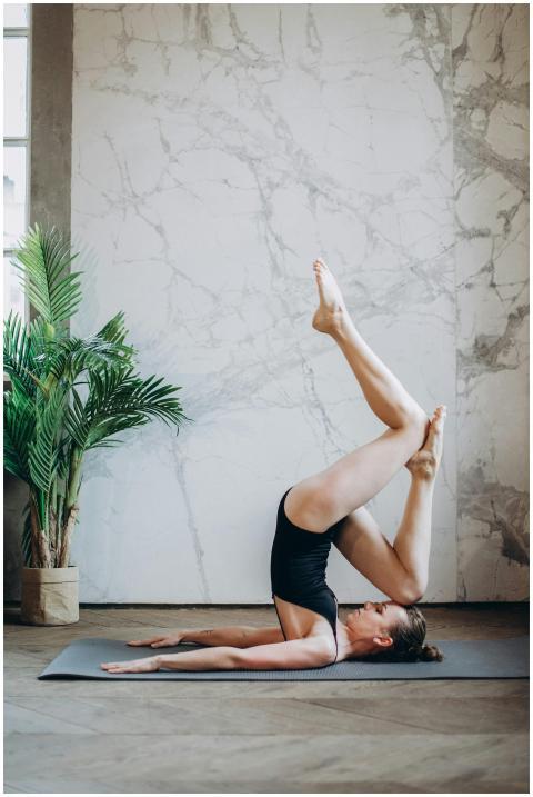A young woman practicing a yoga pose indoors, high