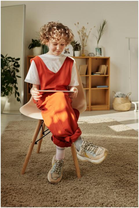 Young boy in red outfit using a tablet while sitti