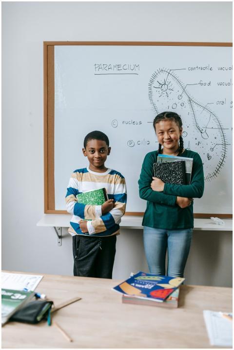Cheerful schoolchildren holding textbooks in a cla