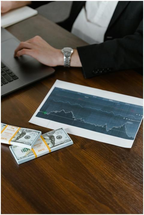 A desk scene with cash bundles, a chart printout,