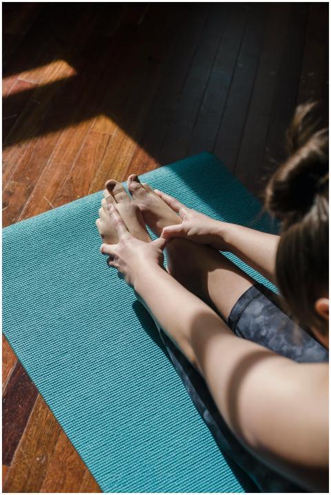 A woman performs a yoga stretch on a blue mat indo