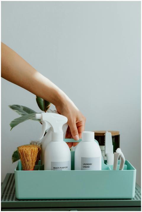 Hand arranging cleaning products in a tidy organiz
